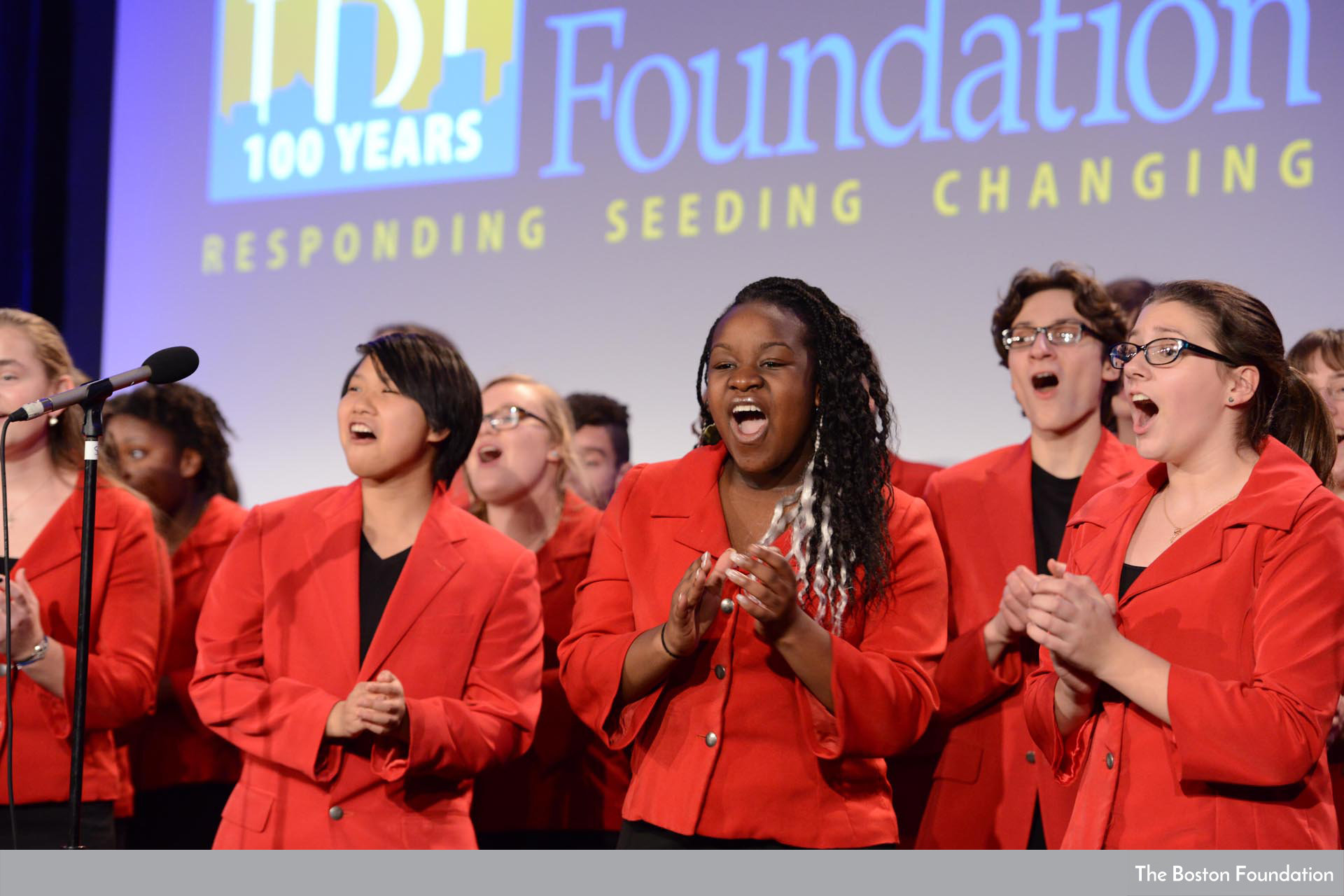 Teens in red jackets sing on stage at The Boston Foundation's centennial